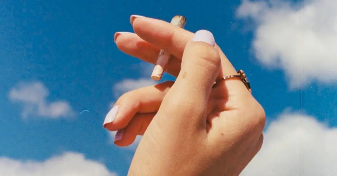 Aged tobacco leaf wrap held delicately against a vibrant blue sky, emphasizing its natural quality